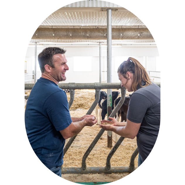 A dairy farmer and a Sollio Agriculture agri-advisor in a cowshed in winter.